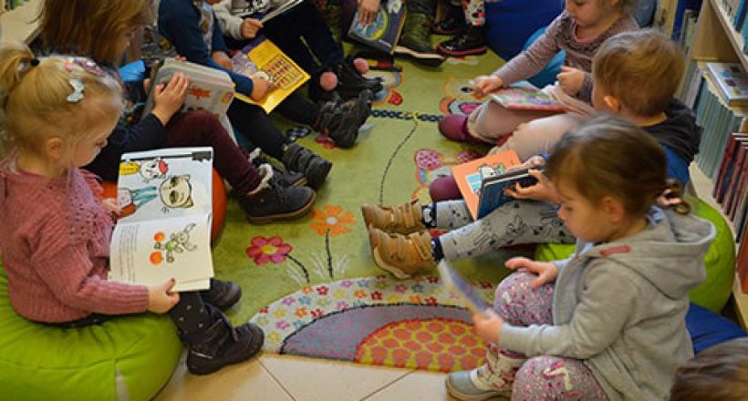 dzieci z przedszkola oglądające książki w bibiliotece