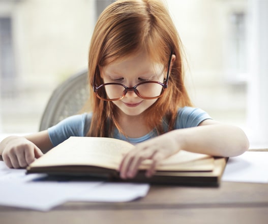 ruda dziewczynka czytająca książkę